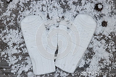 white mittens on the background of snow-covered wood surfaces wi Stock Photo