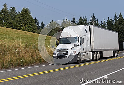 White big rig semi truck transporting dry van semi trailer on th Stock Photo