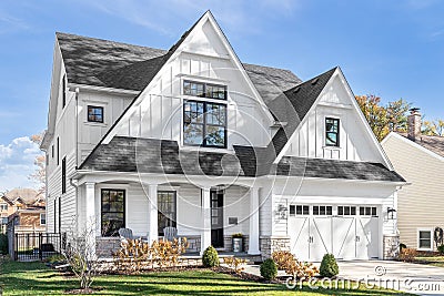 A white modern farmhouse with a black roof. Stock Photo