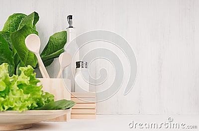 White modern kitchen decor with beige natural wooden dish, utensils, fresh green salad on wood background. Stock Photo