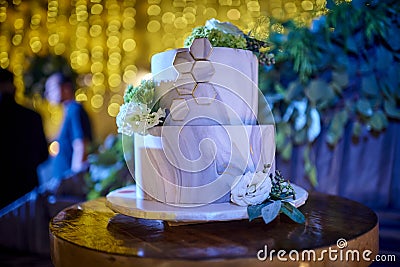 White modern wedding cake over wood table with amber lights Stock Photo