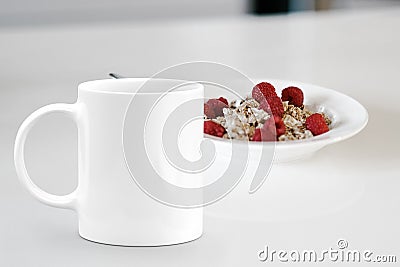 White mug next to a bowl of cereal. Stock Photo