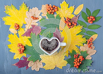 White mug in the shape of a heart with steaming coffee or tea on a background of autumn fallen dry colorful leaves Stock Photo