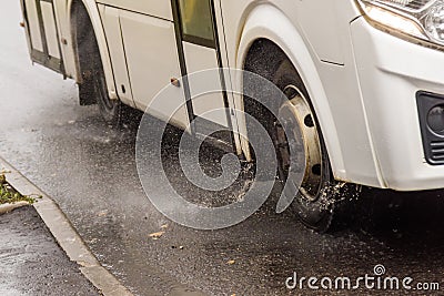 white municipal bus moving on rainy road with water splashes Stock Photo