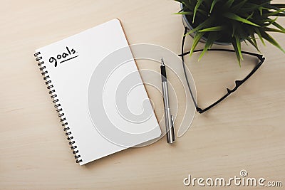 White notebook top view with small goals words on wood table close to pen and glasses Stock Photo