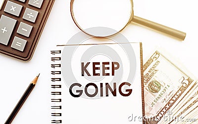 White notepad with the text of the KEEP GOING on the background of dollars and office tools Stock Photo
