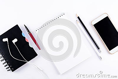 White office desk table with blank notebook, smart phones, headphones and other office supplies. Top view. Copy space. Flat lay Stock Photo