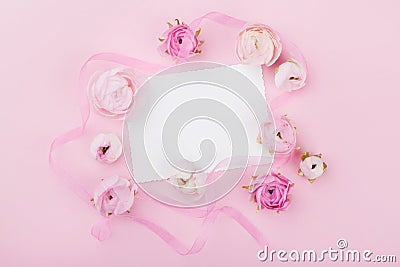 White paper blank and spring flower on pink desk from above for wedding mockup or greeting card on womans day. Floral frame. Stock Photo