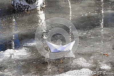 White paper boat in a stream with melted snow with shadows from birches in spring on a sunny day. Spring landscape, snow melting.T Stock Photo