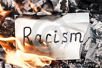 White paper with text of racism in fire. Concept of nationalism and ethnic equality. Social Issues. Discrimination, racial problem Stock Photo