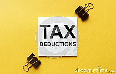 White paper with text Tax Deductions on a yellow background with stationery Stock Photo