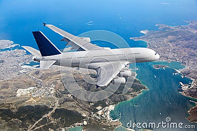 White passenger double decker plane flies high over the sea coast Stock Photo