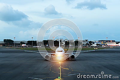 White passenger plane takes off from the airport runway. Aircraft moves against the backdrop of night. Airplane front view. Stock Photo