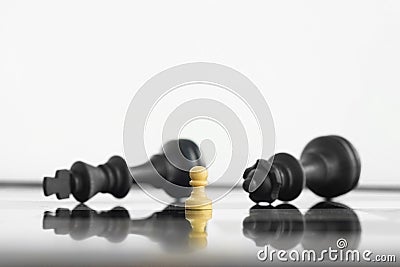 White peon standing victorious in front of a defeated King and Queen black chess army after confrontation Stock Photo
