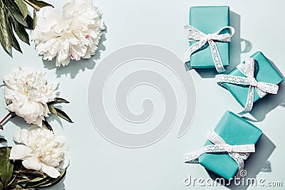 White peonies and turquoise gifts boxes on blue background. Beauty floral background, trendy shadows Stock Photo