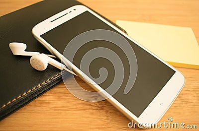 White phone and headphones on the table Stock Photo