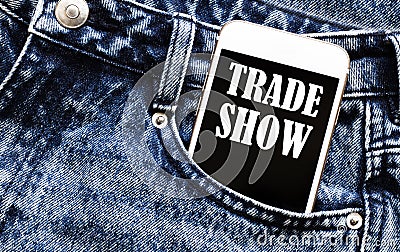 White phone with text Trade Show lies in jeans pocket Stock Photo