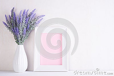 White picture frame with lovely purple flower in vase on white wooden table Stock Photo