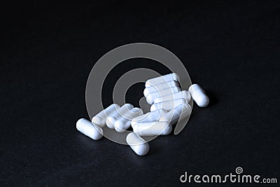 White pills on black background in abstract style on white background. Stock Photo