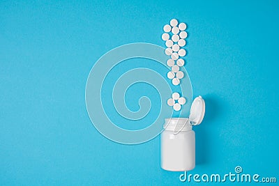 White pills in a exclamation mark poured from a medicine bottle on blue background. Medication and prescription pills. Important i Stock Photo