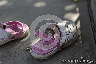 White-pink dirty summer slippers in the shade on a concrete path Stock Photo