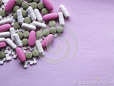 White, pink and green pills on a pink background. multi-colored drugs. Stock Photo