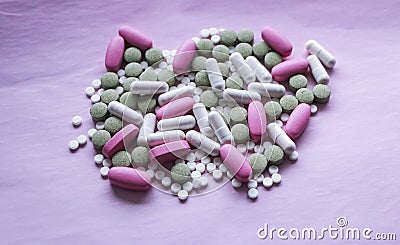 White, pink and green pills on a pink background. multi-colored drugs. Stock Photo