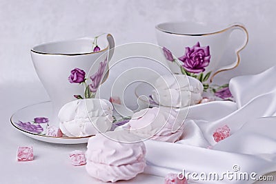 White and pink marshmallows are on the table with beautiful cups for tea Stock Photo