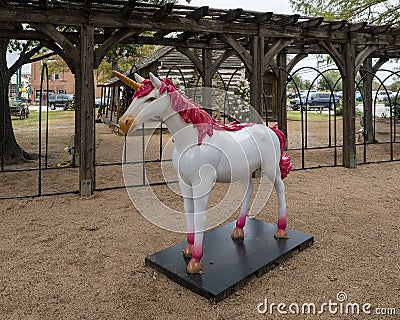 White and pink statue of a unicorn standing on a pedestal along Main Street in historic downtown Grapevine, Texas. Editorial Stock Photo