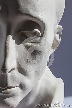 White plaster statue of half mans head on blue grey background Stock Photo