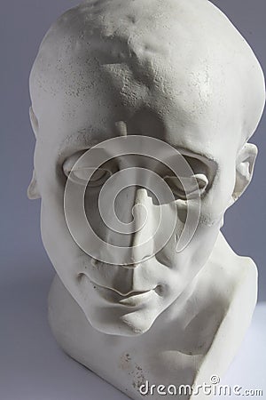 White plaster statue of mans head on blue grey background Stock Photo