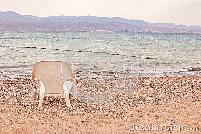 White plastic chair standing on the pebbles stones beach on Red Sea in Eilat Stock Photo