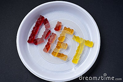 White plastic plate with text DIET from sweet jelly. Sweet fruit gummy bears. Editorial Stock Photo