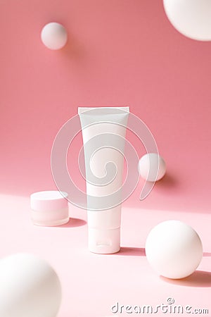 White plastic tube for cosmetic product on pink background with abstract white spheres, front view. Containers for eye moisturizer Stock Photo