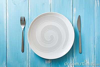 White Plate on blue wooden background with utensils Stock Photo