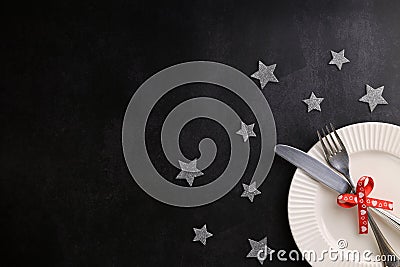 White plate with cutlery tied with red festive ribbon, grey glitter stars round the plate. Place for text Stock Photo