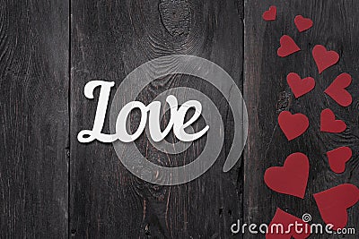 White lettering Love on a rustic background with red cardboard hearts on the side. with place for text Stock Photo