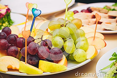 On a white plate sliced apples and grapes. Stock Photo