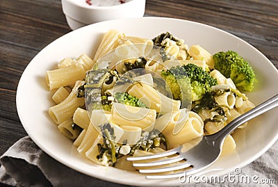 White plate with tortilloni with sauce and spinach and cheese, broccoli, fork, napkin on a light background, spinach pasta, Stock Photo