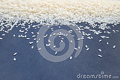 White polished long grain uncooked raw rice on a dark gray blue background, close up Stock Photo