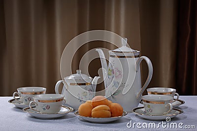 White porcelain tea set with flowers and plate with apricots on a tablecloth Stock Photo
