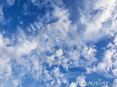 White, puffy clouds in blue sky with jet and con trail Stock Photo