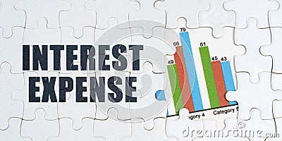 On white puzzles there is an inscription - Interest Expense. Financial graph in the window among the puzzles Stock Photo