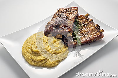 White rectangular plate with baked pork ribs and cornmeal mush Stock Photo