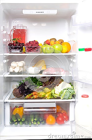 In a white refrigerator, on the top shelf fruits, berries and a jug with compote, on medium mushrooms, poultry meat, cottage Stock Photo