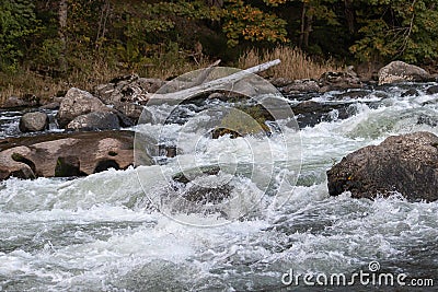 White water rapids over large rocks and boulders Stock Photo