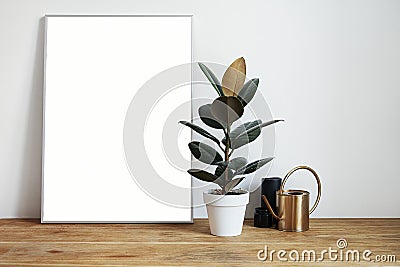 White room interior with green plants on rustic wooden table, modern personal laptop, poster in frame with space for layout Stock Photo