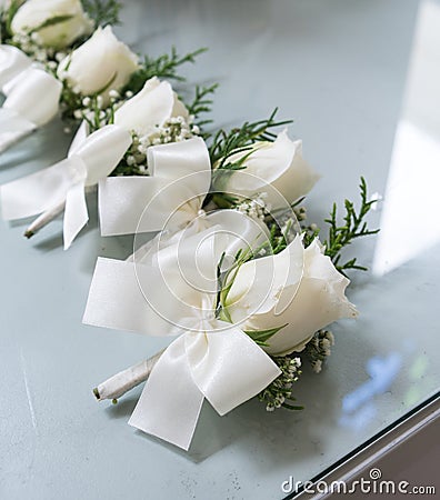 White roses boutonniere with white bow tie ribbon groomsmen on g Stock Photo