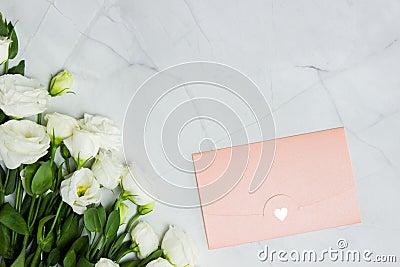 White roses with pink envelop on marble background. Stock Photo