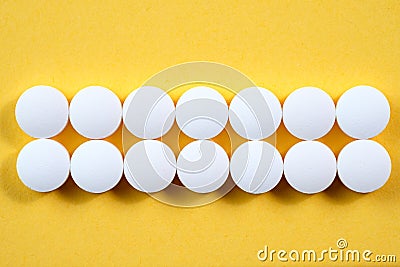 White round pharmaceutical pills on yellow background Stock Photo